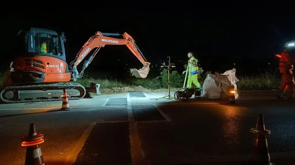 Technicians working at night to install WIM dynamic weighing sensors in road pavement.