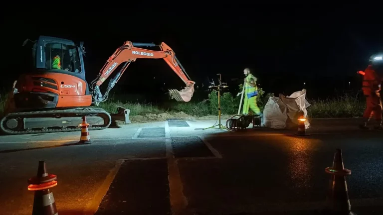 Tecnici al lavoro di notte per installare sensori di pesatura dinamica WIM nella pavimentazione stradale.
